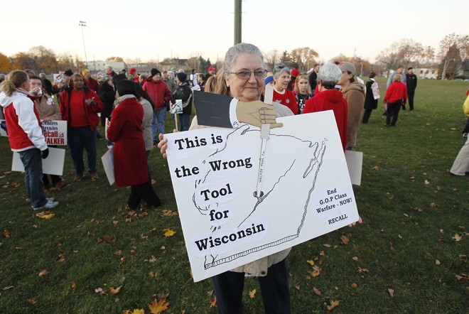 Robin Grabner of Milwaukee holds a sign as protesters gather Tuesday for a Recall Walker rally in Wauwatosa near Juneau High School. They were planning to march to Walker's home. 