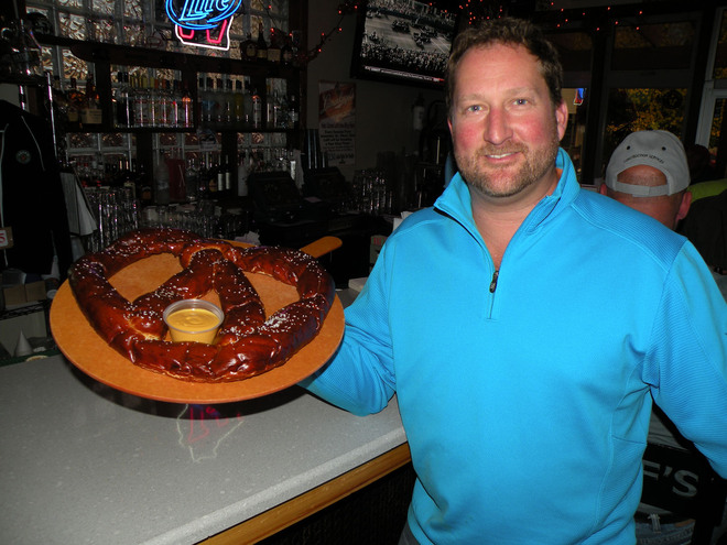 Chris Leffler shows off a giant pretzel, one of Leff’s Lucky Town’s signature offerings, before it is served.