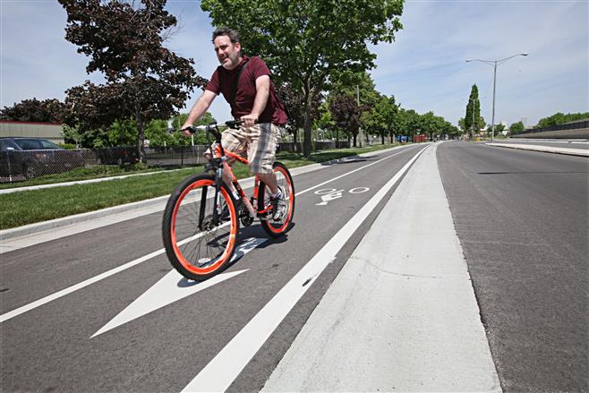 Kelly Ambrose of Milwaukee rides along a new-style bicycle path on pavement raised 4 inches above the auto traffic lane. The bike lane is part of a larger project to improve cycling between Bay View and downtown Milwaukee.