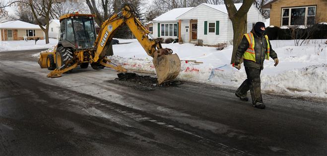 Water Department worker Dan Dimoff walks away from earth-moving equipment after a hydraulic line broke due to sub-zero temperatures at a water main break in the 11900 block of Oxford Place on Tuesday.