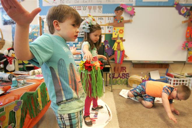 Silas Kwaterski (left) and Madeleine Grandaw keep their balance on their paper surfboards as an imaginary wave tosses Jack Koebert from his ride during a Hawaiian theme day for 4K students at Wauwatosa Catholic School on Jan. 23.