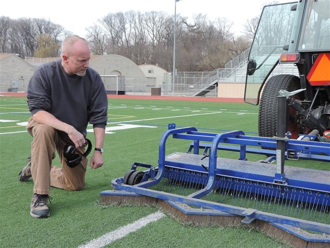Patrick Allen, a park maintenance worker, inspects the grooming machine he uses to help maintain Hart Park’s artificial stadium turf.