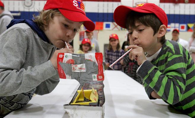 Ryan Westpahl (left) and David Miller propel their team's sailboat along the race trough as one of the activities during the Wauwatosa STEM School’s Recycling Regatta on May 16. Teams created sailboat to race using material recycled from other products.