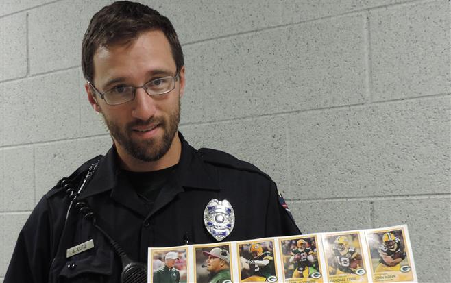 School Resource Officer Joel Kutz holds a display of 2013 Green Bay Packers football cards. Police officers soon will be handing out 2014 cards all over the city.