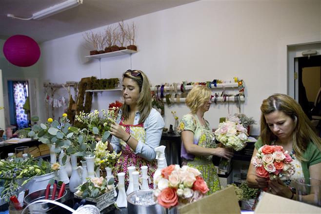 Kaity Thompson (left), Laurel Flannery (center) and Alicia Nass arrange flowers in Bloom Floral & Event.