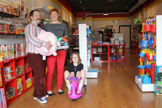 Matthew Poulson, Sarah Fowles, and their daughter Elinor Poulson display their favorite products in the family's new toy store, Ruckus & Glee, at 8730 W. North Ave. in Wauwatosa.