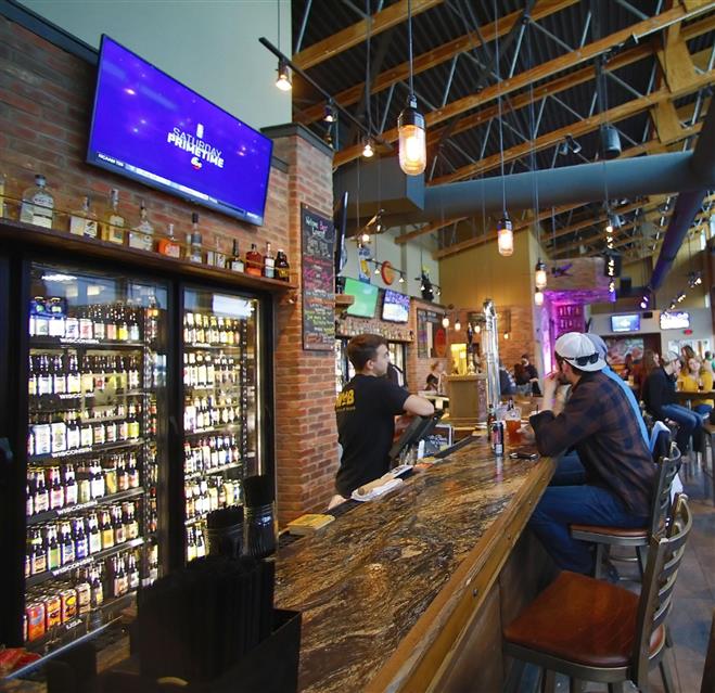 Bartender Eric Preuss pours a tap as Mike Lewitzke enjoys one in the World of Beer tavern recently. The tavern aims to be a place where “people can immerse themselves into a craft beer experience,” said partner Adam Buttina.