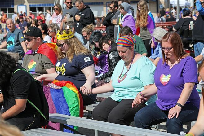 People attending Pridefest on the Summerfest grounds June 12 join hands while a prayer is said for the victims of the Orlando night club shooting. Fear and uncertainty have affected some members of the gay community here.