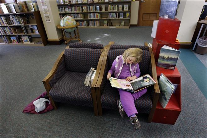 File photo of Katie Knapp of Milwaukee curling up with a good book while visiting the Wauwatosa Public Library.