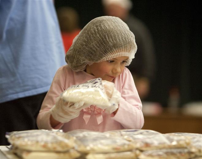 Callie Schneider, 5, of Franklin stacks  a plastic bag containing dehydrated food in St. Matthews Lutheran Church on Oct. 19. The church, along with 600 volunteers, is spending the weekend packaging 200,000 meals for the international charity Worldwide Hunger Relief.