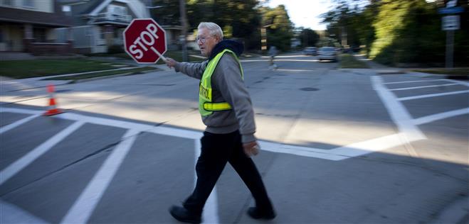 Crossing guard Gerald Brockman stops traffic at the intersection of 68th Street and Aetna Court earlier this month.