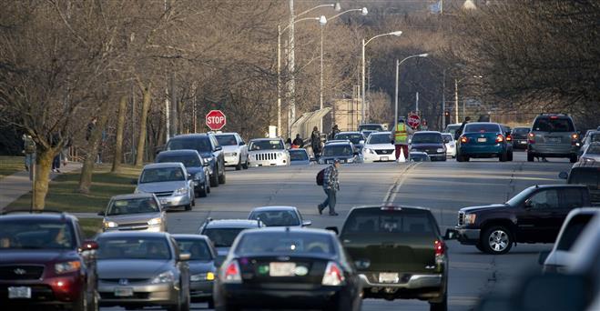 An unidentified Wauwatosa West High School student walks through traffic congestion in front of the school in the 11400 block of West Center Street in December.