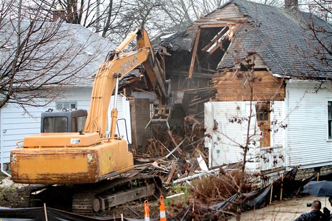 An excavator crushes and packs portions of the front wall, roof, second and first floor inot the basement of a long-vacant home at 1737 Underwood Ave. on May 1 that has been the subject of debate and neighbor concerns for several years.