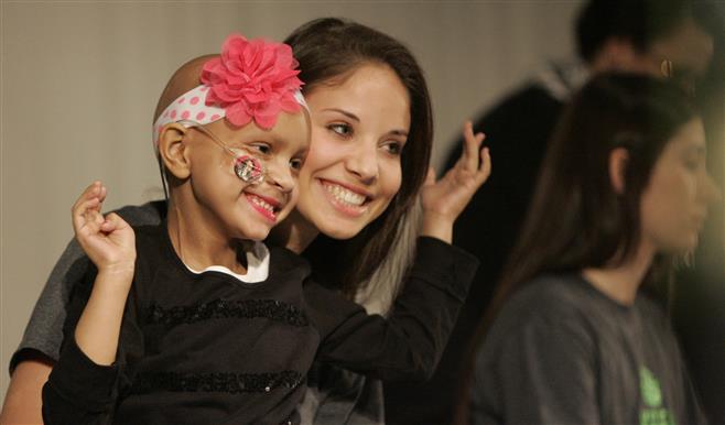 Jayla Rodriguez hams it up with senior Mariella Manzamet-Schmidt as the two were on stage with other donors for the Wauwatosa West Locks of Love on Friday. Jayla was featured in a video about the importance of donations.