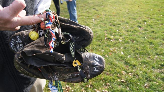 Jim Melchior holds the 50-year-old cleats awarded to the Turkey Bowl MVP each year. Each charm on the cleats was put on by an MVP winner.