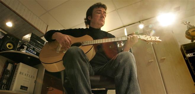 Mark Lansing strums one of the acoustic guitars from his collection in his home studio where he produced his solo CD "Solstice".