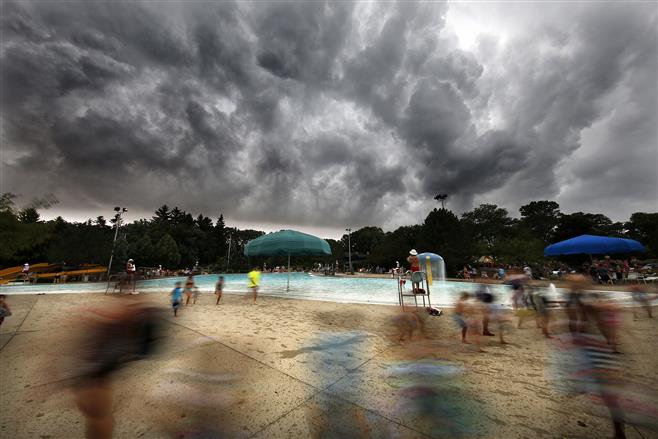 As rains hit, patrons exit the Cool Waters water Park Thursday morning, July 21, 2016, in West Allis, Wisconsin. The pool briefly closed due to the storm.