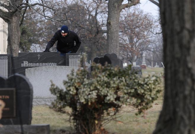 Jay Breitlow has a quiet moment at the grave of his father at Wauwatosa Cemetery Friday, Dec. 5, 2014. Breitlow recently published a book on his father's shooting while he was associate principal at Wauwatosa West High School in 1993.