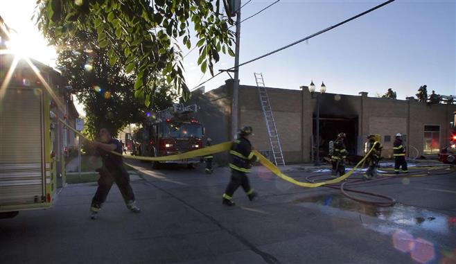 Wauwatosa firefighters pull supply line hose from a truck as they battle a fire at the Sherwin-Williams paint store early Tuesday.